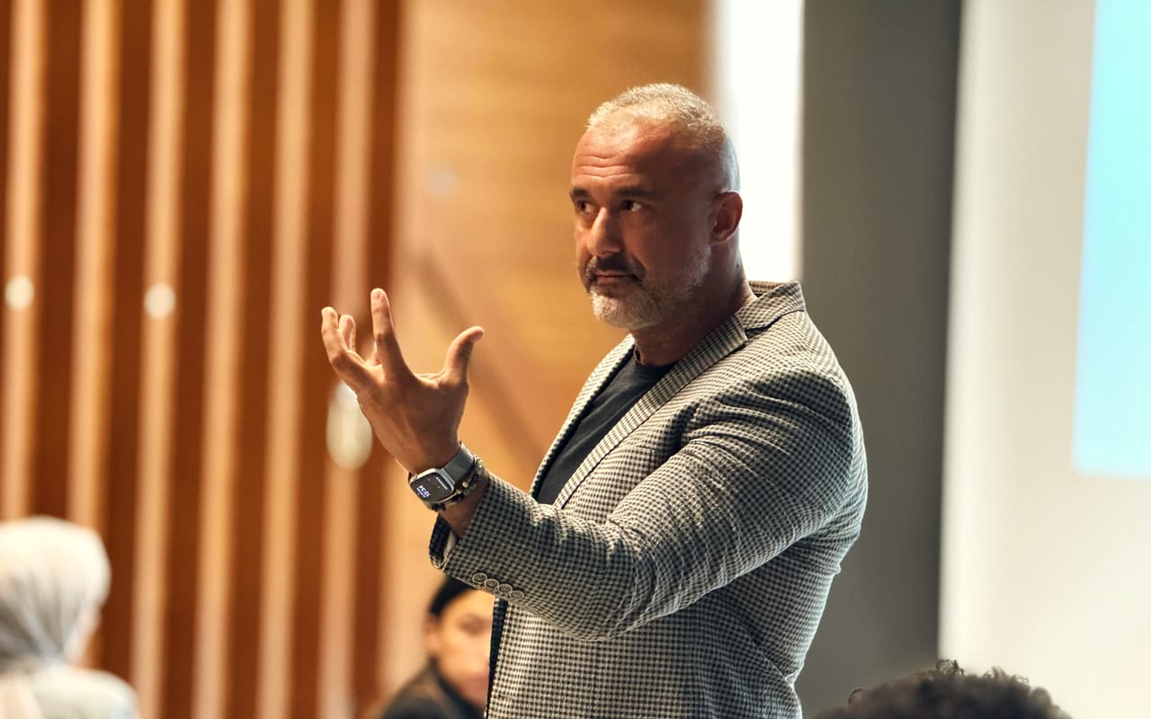 Mehmet Safa Yalçıntaş, dinleyicilerin arasında elleriyle anlatırken